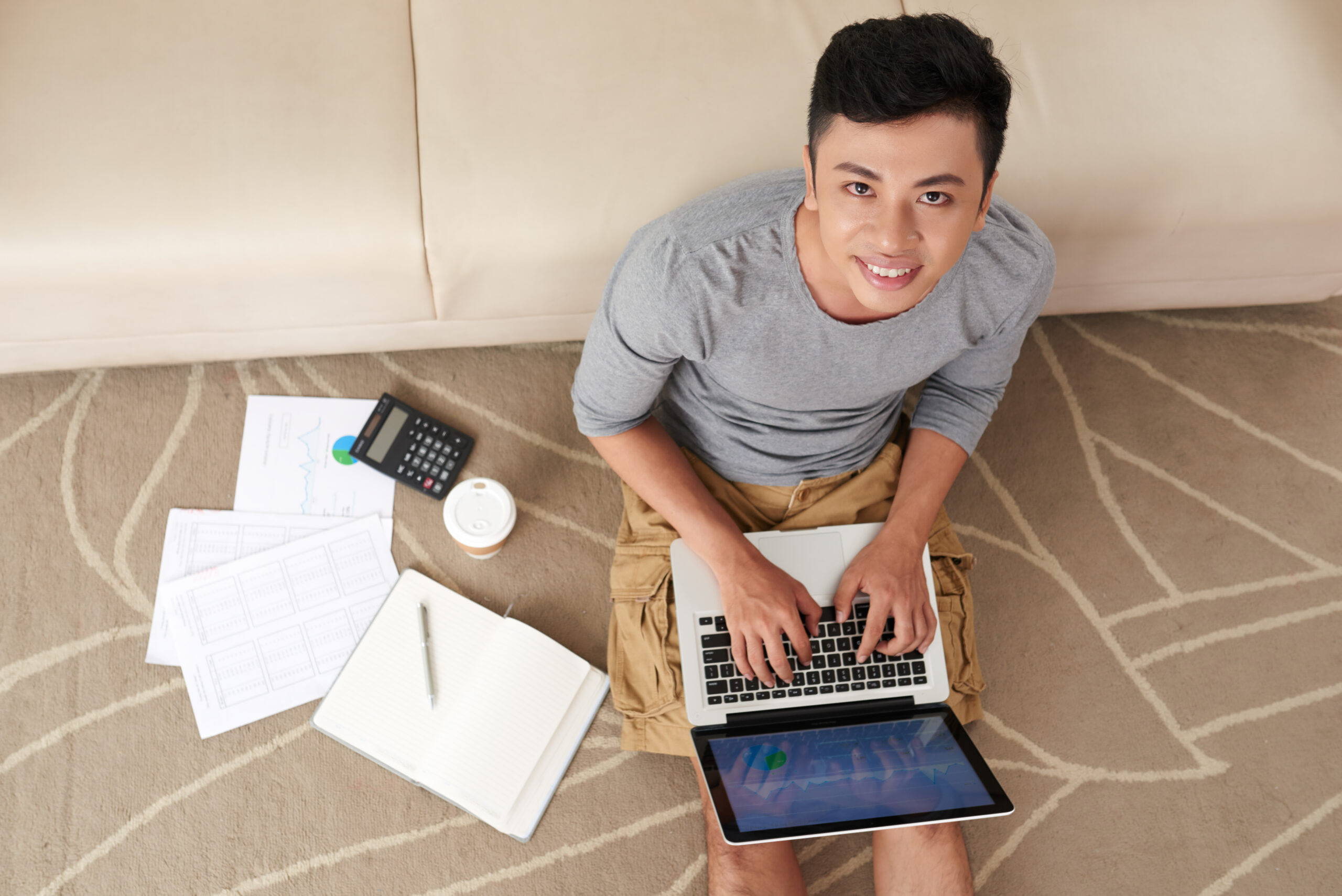 asian-man-working-laptop-sitting-floor-from
